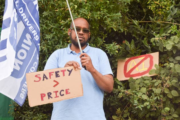 August 4, 2026, London, England, United Kingdom: A protester stands with a Satety over price sign next to an anti-AI sign as members of the App Drivers and Couriers Union (ADCU) gather outside the Waymo depot in Park Royal in protest against Waymo driverless cars. London United Kingdom - ZUMAv130 20260804_zip_v130_007 Copyright: xVukxValcicx