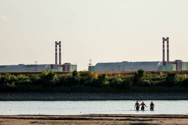 (260803) -- BUDAPEST, Aug. 3, 2026 -- People cool off in the Danube River, with the Paks nuclear power plant in the background, near Dunaszentbenedek, Hungary, Aug. 2, 2026. Hungary is entering its most critical 5 days as dropping water levels on the Danube River threaten the complete shutdown of the Paks nuclear power plant amid an extreme heatwave, Hungary s Prime Minister Peter Magyar said on Sunday, warning that the plant could be shut down for more than a month. (Photo by Xinhua) HUNGARY-NUCLEAR POWER PLANT-POSSIBLE SHUTDOWN DavidxBalogh 