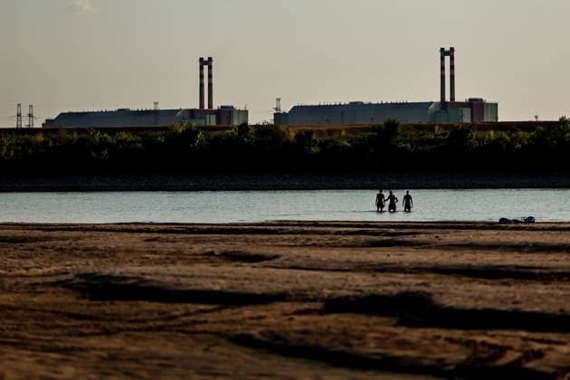 (260803) -- BUDAPEST, Aug. 3, 2026 -- People cool off in the Danube River, with the Paks nuclear power plant in the background, near Dunaszentbenedek, Hungary, Aug. 2, 2026. Hungary is entering its most critical 5 days as dropping water levels on the Danube River threaten the complete shutdown of the Paks nuclear power plant amid an extreme heatwave, Hungary s Prime Minister Peter Magyar said on Sunday, warning that the plant could be shut down for more than a month. (Photo by Xinhua) HUNGARY-NUCLEAR POWER PLANT-POSSIBLE SHUTDOWN DavidxBalogh 
