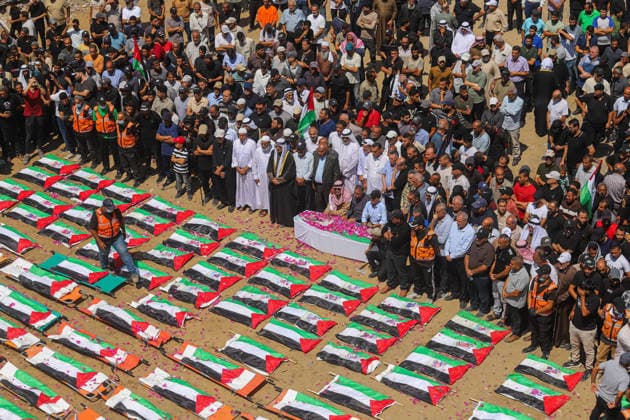 Gaza City Mass Funeral August 3 2026 Mourners gather near rows of bodies wrapped in Palestinian flags during a mass funeral procession in the Al-Sabra neighborhood of Gaza City, Gaza Strip, on August 4, 2026. The remains of 112 members of the Abu Sharia and Al-Hasayneh families were recovered from the rubble of their home following an Israeli strike. Relatives stated the attack claimed the lives of more than 300 people. The bodies were buried at Al-Maamadani Cemetery as military operations continue across the territory. Gaza Gaza Strip Palestinian Territories Copyright: xRamezxHabboubx