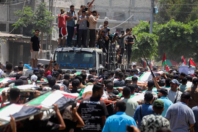 Gaza City Mass Funeral August 3 2026 Mourners carry bodies wrapped in Palestinian flags on stretchers through a street during a mass funeral procession in the Al-Sabra neighborhood of Gaza City, Gaza Strip, on August 4, 2026. The remains of 112 members of the Abu Sharia and Al-Hasayneh families were recovered from the rubble of their home following an Israeli strike. Relatives stated the attack claimed the lives of more than 300 people. The bodies were buried at Al-Maamadani Cemetery as military operations continue across the territory. Gaza Gaza Strip Palestinian Territories Copyright: xRamezxHabboubx