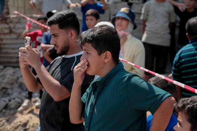 Gaza City Mass Funeral August 3 2026 Mourners stand near a tape barrier during a mass funeral procession in the Al-Sabra neighborhood of Gaza City, Gaza Strip, on August 4, 2026. The remains of 112 members of the Abu Sharia and Al-Hasayneh families were recovered from the rubble of their home following an Israeli strike. Relatives stated the attack claimed the lives of more than 300 people. The bodies were buried at Al-Maamadani Cemetery as military operations continue across the territory. Gaza Gaza Strip Palestinian Territories Copyright: xEyadxAzamx