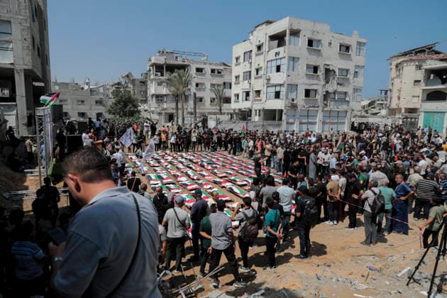 Gaza City Mass Funeral August 3 2026 Mourners gather around rows of bodies wrapped in Palestinian flags during a mass funeral procession in the Al-Sabra neighborhood of Gaza City, Gaza Strip, on August 4, 2026. The remains of 112 members of the Abu Sharia and Al-Hasayneh families were recovered from the rubble of their home following an Israeli strike. Relatives stated the attack claimed the lives of more than 300 people. The bodies were buried at Al-Maamadani Cemetery as military operations continue across the territory. Gaza Gaza Strip Palestinian Territories Copyright: xEyadxAzamx