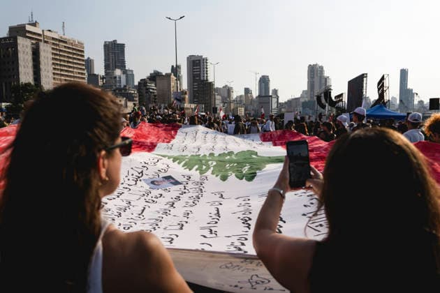 Beirut Port Blast Anniversary Commemoration A woman photographs a large Lebanese flag covered with handwritten messages during a commemoration marking the sixth anniversary of the Beirut Port explosion in Beirut, Lebanon, on August 4, 2026. The August 4, 2020 blast, caused by ammonium nitrate stored at the port, killed more than 200 people, injured thousands and devastated large parts of the Lebanese capital. Beirut Beirut Lebanon Copyright: xManonxRocax