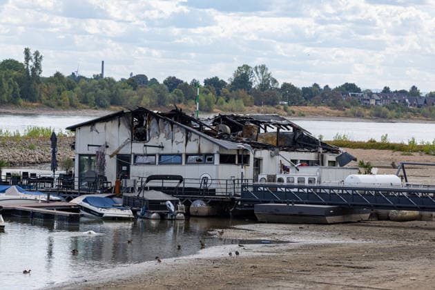 Sürther Bootshaus in Köln einen Tag nach dem Großbrand Ein Tag nach dem Großbrand: Das Sürther Bootshaus in Köln-Sürth, ein beliebtes Ausflugslokal und Restaurant direkt am Rhein, liegt in Trümmern bei dem Feuer am 04.08.2026 brannte vor allem der Dachbereich vollständig aus. Rund 100 Einsatzkräfte der Feuerwehr waren im Großeinsatz, verletzt wurde niemand, die Brandursache ist weiterhin unklar. Köln Sürth Nordrhein-Westfalen Deutschland *** The Sürth Boathouse in Cologne, One Day After the Major Fire One day after the major fire, the Sürth Boathouse in Cologne-Sürth, a popular destination for day trips and a restaurant right on the Rhine, lies in ruins following the fire on August 4, 2026. The roof area, in particular, bur Copyright: xMarcxJohnx