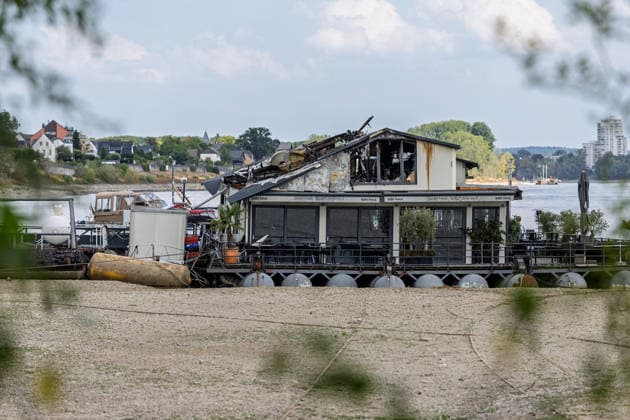 Sürther Bootshaus in Köln einen Tag nach dem Großbrand Ein Tag nach dem Großbrand: Das Sürther Bootshaus in Köln-Sürth, ein beliebtes Ausflugslokal und Restaurant direkt am Rhein, liegt in Trümmern bei dem Feuer am 04.08.2026 brannte vor allem der Dachbereich vollständig aus. Rund 100 Einsatzkräfte der Feuerwehr waren im Großeinsatz, verletzt wurde niemand, die Brandursache ist weiterhin unklar. Köln Sürth Nordrhein-Westfalen Deutschland *** The Sürth Boathouse in Cologne, One Day After the Major Fire One day after the major fire, the Sürth Boathouse in Cologne-Sürth, a popular destination for day trips and a restaurant right on the Rhine, lies in ruins following the fire on August 4, 2026. The roof area, in particular, bur Copyright: xMarcxJohnx