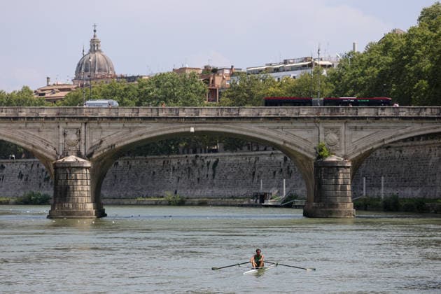 (260805) -- ROME, Aug. 5, 2026 -- A man rows a boat on the Tiber River in Rome, Italy, Aug. 5, 2026. Italy is battling its fourth major heatwave of the summer, with temperatures climbing above 40 degrees Celsius in parts of the country, and a record number of cities placed under the highest heat alert. Authorities are stepping up emergency measures amid mounting health, wildfire and agricultural concerns. The latest heatwave reached its peak on Monday, when the Health Ministry placed 25 of the country s 27 monitored cities under red alert, the highest warning level possible issued for extreme heat. ) ITALY-ROME-TIBER RIVER-HEAT WAVE WangxKaiyan 