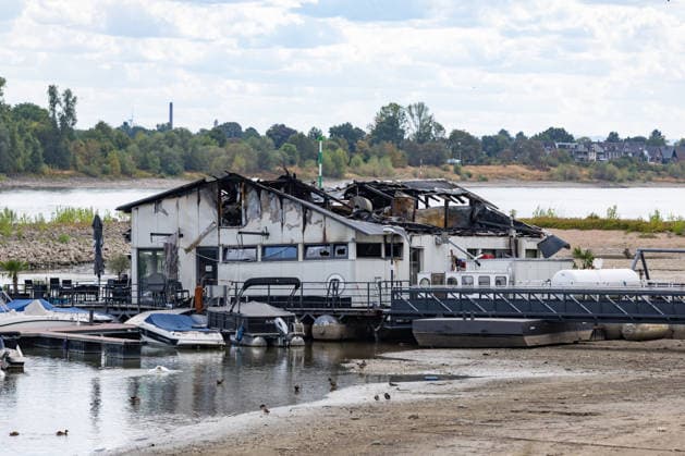 Sürther Bootshaus in Köln einen Tag nach dem Großbrand Ein Tag nach dem Großbrand: Das Sürther Bootshaus in Köln-Sürth, ein beliebtes Ausflugslokal und Restaurant direkt am Rhein, liegt in Trümmern bei dem Feuer am 04.08.2026 brannte vor allem der Dachbereich vollständig aus. Rund 100 Einsatzkräfte der Feuerwehr waren im Großeinsatz, verletzt wurde niemand, die Brandursache ist weiterhin unklar. Köln Sürth Nordrhein-Westfalen Deutschland *** The Sürth Boathouse in Cologne, One Day After the Major Fire One day after the major fire, the Sürth Boathouse in Cologne-Sürth, a popular destination for day trips and a restaurant right on the Rhine, lies in ruins following the fire on August 4, 2026. The roof area, in particular, bur Copyright: xMarcxJohnx