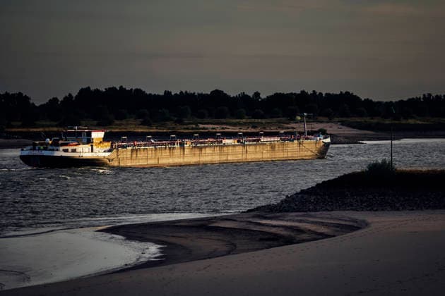 August 6, 2026, Nijmegen, Gelderland, Netherlands: At sunrise near NIJMEGEN, a cargo barge sails upstream on the WAAL towards GERMANY, passing the exposed sandy riverbed that has emerged due to critically low water levels. This main Dutch branch of the RHINE is currently experiencing historic lows caused by prolonged drought, forcing inland vessels to operate with sharply reduced loads and driving up costs across the supply chain. Credit : ZUMA Press Nijmegen Netherlands - ZUMAv145 20260806_zip_v145_002 Copyright: xNorbertxVoskensx