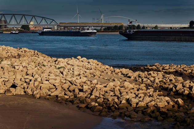 August 6, 2026, Nijmegen, Gelderland, Netherlands: Rising transport costs and disrupted supply chains are already hitting industries across the Netherlands and Germany as prolonged drought forces inland vessels on the WAAL to sail with sharply reduced loads. Under the WAALBRUG near NIJMEGEN, looking downstream, cargo ships including the ANASTACIA pass the exposed rocky riverbank, with the railway bridge visible in the background on this main Dutch branch of the RHINE, where water levels have dropped to historic lows. Credit : ZUMA Press Nijmegen Netherlands - ZUMAv145 20260806_zip_v145_009 Copyright: xNorbertxVoskensx