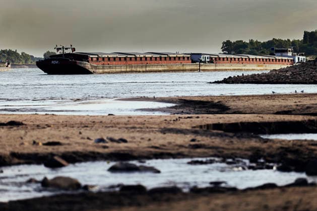 News Bilder des Tages August 6, 2026, Nijmegen, Gelderland, Netherlands: The cracked and exposed riverbed of the WAAL near OOIJ stretches into the distance as a cargo barge sails upstream towards GERMANY. Prolonged drought has reduced water levels on this main Dutch branch of the RHINE to historic lows, forcing inland vessels to operate with sharply reduced loads and driving up transport costs. Credit : ZUMA Press Nijmegen Netherlands - ZUMAv145 20260806_zip_v145_010 Copyright: xNorbertxVoskensx