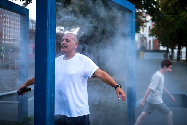 (260806) -- BUDAPEST, Aug. 6, 2026 -- People cool off under a misting system in Budapest, Hungary, Aug. 6, 2026. Hungarian authorities on Tuesday extended the country s highest-level heat alert until midnight on Friday as forecasts indicate the ongoing heatwave will continue across the country. (Photo by h Xinhua) HUNGARY-BUDAPEST-HEAT WAVE DavidxBalog 