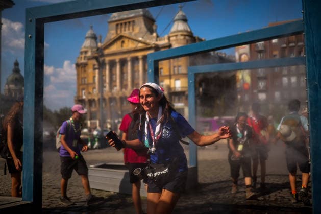 (260806) -- BUDAPEST, Aug. 6, 2026 -- People cool off under a misting system in Budapest, Hungary, Aug. 6, 2026. Hungarian authorities on Tuesday extended the country s highest-level heat alert until midnight on Friday as forecasts indicate the ongoing heatwave will continue across the country. (Photo by h Xinhua) HUNGARY-BUDAPEST-HEAT WAVE DavidxBalog 
