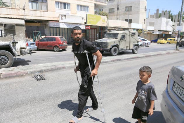 August 6, 2026, Nablus, Palestine: A Palestinian man and his child walk past Israeli military vehicles during a military operation in the Askar refugee camp, east of Nablus in the West Bank. The raid is part of a broader military campaign targeting refugee camps in the West Bank. The Israeli government has threatened to occupy refugee camps, in areas under the control of Palestinian President Mahmoud Abbas. Nablus Palestine  - ZUMAs197 20260806_aaa_s197_112 Copyright: xNasserxishatyehx