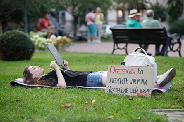 Activist Works On Tablet PC During Rally Against Dismissal Of Mykhailo Fedorov - Kyiv An activist lying on a sleeping pad on the lawn works on a tablet PC during a peaceful protest against the dismissal of Mykhailo Fedorov from the post of Ukraine s Defence Minister in Ivana Franka Square outside the Ivan Franko National Academic Drama Theatre, close to the Office of the President, Kyiv, Ukraine on August 6, 2026. Large-scale cardboard rallies in support of former Defence Minister Mykhailo Fedorov have been held in Kyiv and other cities across Ukraine for 22 consecutive days. On July 14, 2026, the Ukrainian Parliament accepted the resignation of Prime Minister Yuliia Svyrydenko, leading to the resignation of the Cabinet. On July 15, 2026,  Copyright: xUkrinform ABACAx