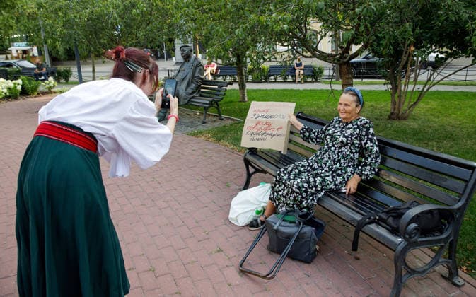 Woman In Traditional Costume At Rally Against Dismissal Of Mykhailo Fedorov - Kyiv A woman in a traditional folk costume takes a picture of an elderly woman sitting on a bench with a placard during a peaceful protest against the dismissal of Mykhailo Fedorov from the post of Ukraine s Defence Minister in Ivana Franka Square outside the Ivan Franko National Academic Drama Theatre, close to the Office of the President, Kyiv, Ukraine on August 6, 2026. Large-scale cardboard rallies in support of former Defence Minister Mykhailo Fedorov have been held in Kyiv and other cities across Ukraine for 22 consecutive days. On July 14, 2026, the Ukrainian Parliament accepted the resignation of Prime Minister Yuliia Svyrydenko, leading to the resignati  Copyright: xUkrinform ABACAx