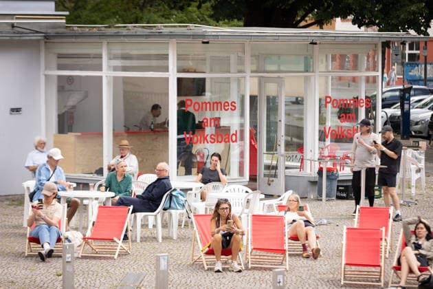 Die Volksbuehne hat am 07.08.2026 ein Pop-up-Freibad in Berlin-Mitte eroeffnet (Foto vom 07.08.2026, im Bild: Liegestuehle vor Pommes-Verkauf). Das Volksbad ist das erste Projekt des neuen Intendanten Matthias Lilienthal. In dem 25 Meter langen und 1,30 Meter tiefen Becken auf dem Rosa-Luxemburg-Platz koennen Besucher nach Buchung eines Zeitslots kostenlos und ohne Ausweispflicht schwimmen gehen, wie das Theater auf seiner Website angibt. Die fuer acht Wochen geplante Aktion sorgt aber wegen hoher Kosten auch fuer Kritik. (Siehe epd-Meldung vom 07.08.2026) EDITORIAL USE ONLY *** On August 7, 2026, the Volksbühne opened a pop-up outdoor pool in Berlin-Mitte. Photo from August 7, 2026, showing lounge chairs in front of a French fry stand. T Copyright: epd-bild HansxScherhaufer HSR62863