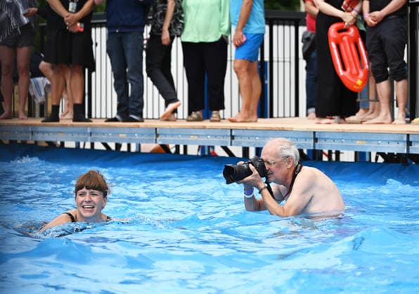 Temporary swimming pool opened in front of the Volksbuehne theatre in Berlin BERLIN, GERMANY - AUGUST 07: An elderly man takes photos of a woman as people swim and visit the newly opened Volksbad, a temporary public swimming pool installed in front of the Volksbuehne theatre at Rosa-Luxemburg-Platz in Berlin, Germany, on August 07, 2026. To mark the start of the Volksbuehne’s new artistic directorship, a temporary public swimming pool with a 25-meter swimming lane has been installed on the square for eight weeks. Volodymyr Sindieiev Anadolu Berlin Germany. Editorial use only. Please get in touch for any other usage.  Copyright: x2026xAnadoluxVolodymyrxSindieievx