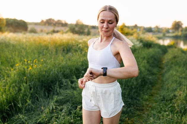 Woman running outdoors checking smartwatch during fitness workout model released, Symbolfoto, MKVF00286