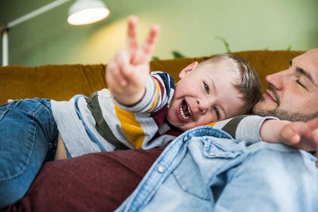A smiling son enjoys fun time with his father on the couch at home model released, Symbolfoto property released, UUF37372