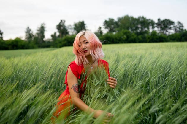 A woman in a red dress touches green wheat in a summer field model released, Symbolfoto, VCF01730