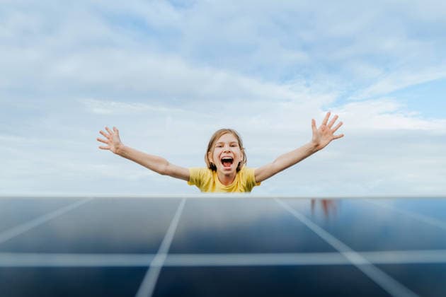 Happy girl celebrates green energy behind a solar panel outdoors model released, Symbolfoto property released, YTF05009