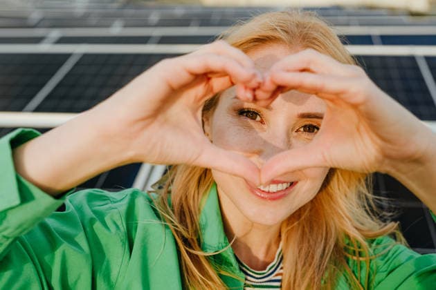 Smiling woman making heart shape near solar panel outdoors model released, Symbolfoto property released, YTF05043
