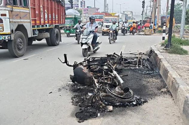 PATNA, INDIA - AUGUST 7: A two-wheeler set ablaze by an angry mob after a speeding bus struck and fatally ran over a 22-year-old local resident Manish Kumar along National Highway 30 near the Zero Mile intersection under the Agamkuan police station limits on August 7, 2026 in Patna, India. Incensed by the fatal hit-and-run incident, angry residents and eyewitnesses staged a road blockade, vandalized passing vehicles including public transport bus, three police vehicles, and several two-wheelers. The mob also pelted stones at responding law enforcement teams.(Photo by Santosh Kumar Hindustan Times) Angry Mob Torches Bus, Police Vehicles After Youth Killed by Speeding Bus In Patna