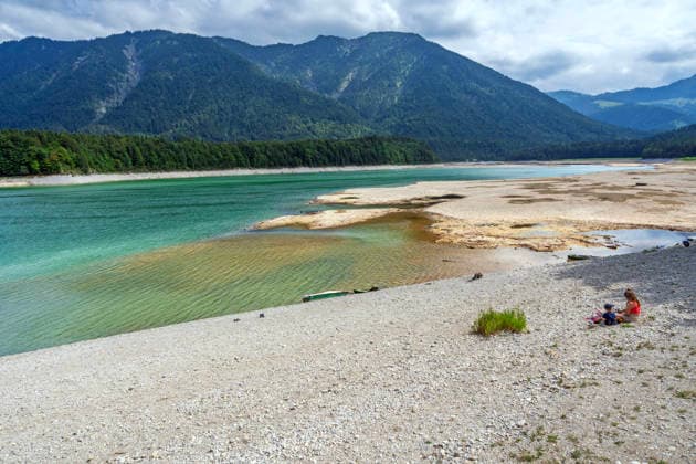 Der Wasserspiegel des Sylvensteinspeichers ist wegen anhaltender Trockenheit deutlich gesunken, breite Uferstreifen sind trocken gefallen, das Niedrigwasser sorgt für breite Kiesflächen, Bayerische Alpen, Lenggries, 7. August 2026 Deutschland, Lenggries-Fall, 7. August 2026, breite Kiesflächen am Ufer des Sylvensteinspeichers, die anhaltende Trockenheit hat den Wasserspiegel des Sylvensteinspeichers deutlich sinken lassen, breite Uferstreifen sind trocken gefallen, Niedrigwasser sorgt für einen breiten Kiesstrand, Menschen am Ufer, künstlicher Speichersee in den Bayerischen Voralpen bei Lenggries, Wasserspeicher zur Regulierung der Isar, Hochsommer, heißer Sommertag, Freitagnachmittag, Landkreis Bad Tölz-Wolfratshausen, Oberbayern,