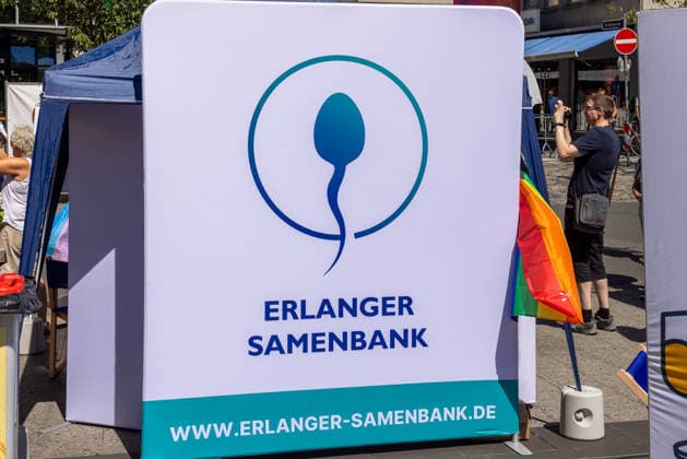 CSD Nürnberg 2026 Nürnberg Pride Week, Nürnberg, 08.08.2026 Werbetafel der Erlanger Samenbank auf dem Kornmarkt während des Christopher Street Day. Im Hintergrund fotografiert ein Passant das Geschehen, eine Regenbogenfahne ist aufgestellt. Nürnberg Bayern Deutschland *** CSD Nuremberg 2026 Nuremberg Pride Week, Nuremberg, August 8, 2026 A billboard for the Erlangen Sperm Bank on the Kornmarkt during Christopher Street Day. In the background, a passerby is taking a photo of the scene; a rainbow flag is on display. Nuremberg, Bavaria, Germany 20260808-286A4832-M4000