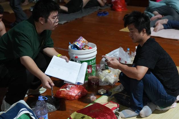 (260808) -- TAIZHOU, Aug. 8, 2026 -- A staff member (L) inquires a resident about his needs at a temporary shelter in a middle school in Yuhuan, Taizhou City, east China s Zhejiang Province, Aug. 8, 2026. Coastal areas of eastern China were bracing for strong winds and torrential rain as Typhoon Dolphin approached, prompting authorities to recall fishing boats, suspend ferry services and prepare for evacuations. China s meteorological authority on Saturday upgraded its emergency response for Dolphin to Level III and raised the typhoon warning from yellow to orange. ) CHINA-ZHEJIANG-TYPHOON DOLPHIN-PREVENTION (CN) HuangxZongzhi 