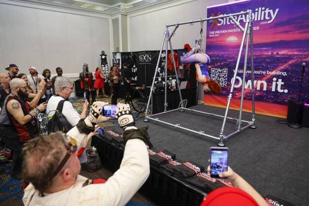 August 8, 2026, St. Petersburg, Florida, USA: Attendees watch Zonah dressed as Spider Woman hang from BDSM rigging frame during the Fetish Con trade show on Saturday, Aug. 8, 2026 in St. Petersburg. St. Petersburg USA - ZUMAs70_ 20260808_zan_s70_012 Copyright: xLuisxSantanax