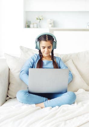Ein Schulmädchen mit Kopfhörern sitzt auf dem Sofa und arbeitet an einem Laptop Ein Schulmädchen mit Kopfhörern sitzt auf dem Sofa und arbeitet an einem Laptop (License=RF) ,model released, Symbolfoto Copyright: xZoonar.com RaisaxKanarevax 25366768 ,model released, Symbolfoto ,property released