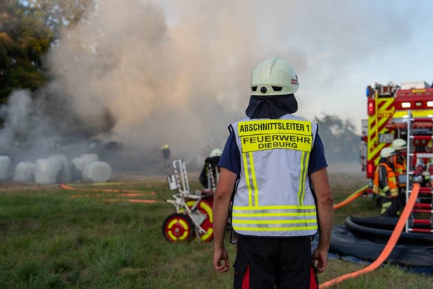 Strohballenlager brennt Feuer greift auf Wald über rund 70 Kräfte im Einsatz Am Samstag den 08.08.2026, geriet gegen 19:15 Uhr ein Strohballenlager im Großwiesenweg in Dieburg in Brand. Von rund 30 bis 40 gelagerten Großballen fingen etwa 10 bis 12 Feuer, die Flammen griffen zudem auf ein angrenzendes Waldstück über, das die Einsatzkräfte in Riegelstellung sicherten. Rund 70 Kräfte der Feuerwehren aus Dieburg, Münster und Groß-Zimmern rückten aus und löschten die Ballen mit Tanklöschfahrzeugen und Unterstützung von Traktoren. Die Rauchentwicklung hätte in Richtung der Bundesstraße 45 zu Sichtbehinderungen führen können. Die Brandursache war zunächst unklar und sollte von der Polizei ermittelt werden. Dieburg Hess