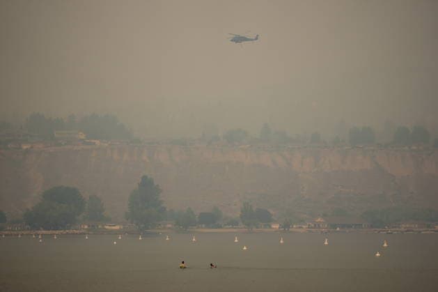 August 9, 2026, Penticton, Bc, CANADA: People float in the water while a helicopter being used to battle wildfires flies overhead as smoke from the Bald Range wildfire envelops Okanagan Lake, in Penticton, B.C., on Sunday, Aug. 9, 2026. The Bald Range wildfire in British Columbia s south Okanagan region has forced 20,000 people out of their homes in the Peachland and Summerland areas. Penticton CANADA  - ZUMAc35_ 20260809_zaf_c35_057 Copyright: xDarrylxDyckx