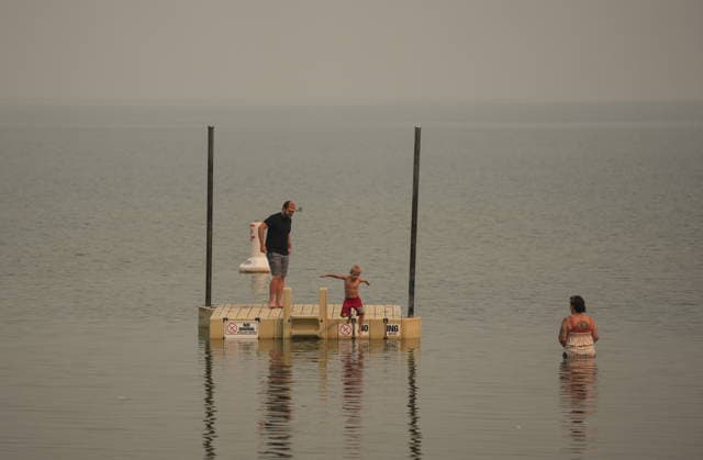 August 9, 2026, Penticton, Bc, CANADA: A young boy jumps into the water as smoke from the Bald Range wildfire envelops Okanagan Lake, in Penticton, B.C., on Sunday, Aug. 9, 2026. The Bald Range wildfire in British Columbia s south Okanagan region has forced 20,000 people out of their homes in the Peachland and Summerland areas. Penticton CANADA  - ZUMAc35_ 20260809_zaf_c35_058 Copyright: xDarrylxDyckx