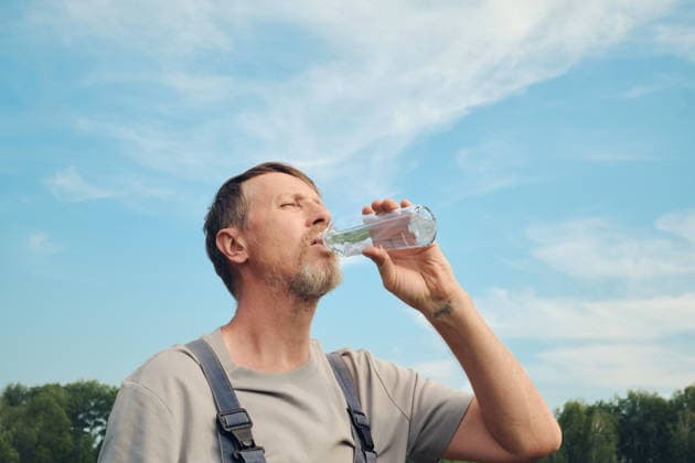 Ein Mann, der an einem warmen Tag unter blauem Himmel Flüssigkeit zu sich nimmt und seinen Durst stillt Man hydrating and quenching thirst under a blue sky on a warm day (License=RF) ,model released, Symbolfoto Copyright: xZoonar.com ElenaxNazarovax 25382914 ,model released, Symbolfoto ,property released
