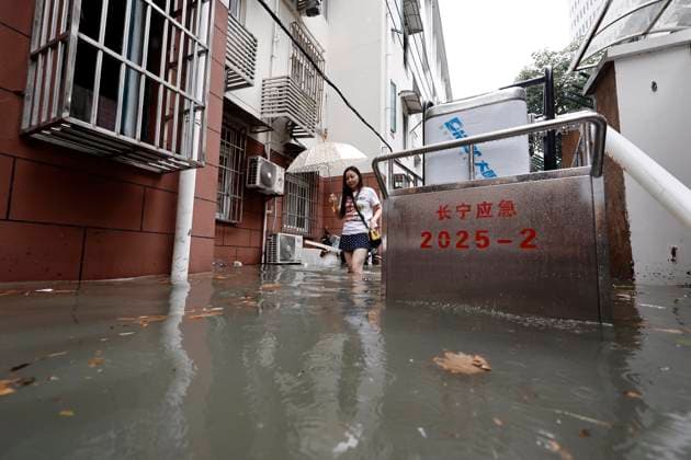 SHANGHAI, CHINA - AUGUST 09: A resident wades through floodwaters in a residential area on August 9, 2026 in Shanghai, China. The Shanghai Meteorological Observatory upgraded the rainstorm warning signal for the central urban area from orange to red at 10:30 a.m. due to the impact of Typhoon Dolphin.  Copyright: xChinaxNewsxServicex 111658975264