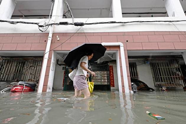 SHANGHAI, CHINA - AUGUST 09: A resident wades through floodwaters in a residential area on August 9, 2026 in Shanghai, China. The Shanghai Meteorological Observatory upgraded the rainstorm warning signal for the central urban area from orange to red at 10:30 a.m. due to the impact of Typhoon Dolphin.  Copyright: xChinaxNewsxServicex 111658975274