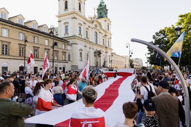 August 9, 2026, Warsaw, Poland: Participants hold a large Belarusian white-red-white national flag during an evening rally marking the sixth anniversary of the August 2020 presidential election in Belarus. An evening gathering marking the sixth anniversary of the August 2020 presidential election in Belarus was held near the Nicolaus Copernicus Monument in central Warsaw, bringing together leaders of Belarusian democratic forces, public figures and activists, as well as several hundred participants. Warsaw Poland  - ZUMAs197 20260809_aaa_s197_106 Copyright: xVolhaxShukailax