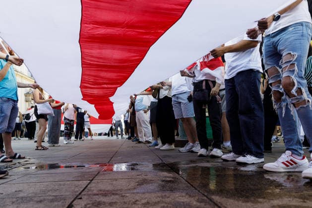 August 9, 2026, Warsaw, Poland: Participants carry a large white-red-white Belarusian flag during an evening rally marking the sixth anniversary of the August 2020 presidential election in Belarus. An evening gathering marking the sixth anniversary of the August 2020 presidential election in Belarus was held near the Nicolaus Copernicus Monument in central Warsaw, bringing together leaders of Belarusian democratic forces, public figures and activists, as well as several hundred participants. Warsaw Poland  - ZUMAs197 20260809_aaa_s197_107 Copyright: xVolhaxShukailax