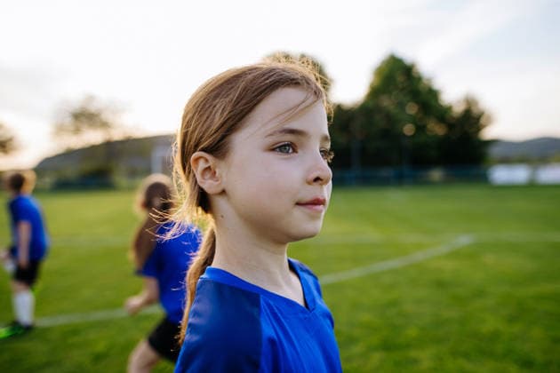 Girl football player standing on sports field before training. Footbal player standing on sports field before training. model released