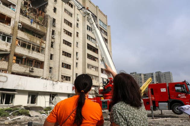 Two women watch rescue workers use a turntable ladder to extinguish a fire in a 10-storey apartment block in the Saltivskyi district hit by a Russian S8000 Banderol cruise missile, Kharkiv, Ukraine, August 9, 2026. As a result of the terrorist attack, the seventh to tenth floors were destroyed. At present, three people are confirmed dead and 37 others injured. (Photo by Viacheslav Madiievskyi Ukrinform) Russian Banderol missile strikes apartment block in Kharkiv  Copyright: xViacheslavxMadiievskyix