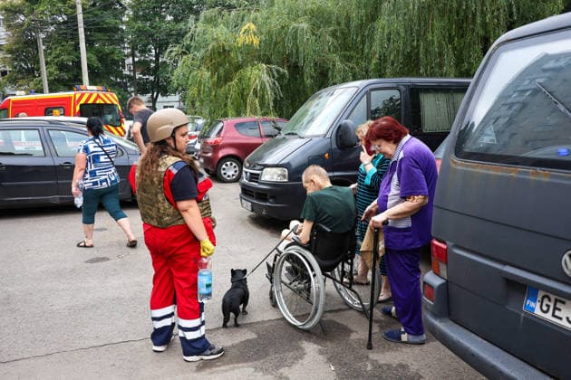Russian Missile Strikes Apartment Block - Kharkiv A paramedic stands by residents during a response effort to a Russian S8000 Banderol cruise missile strike on a 10-storey apartment block in the Saltivskyi district, Kharkiv, Ukraine, August 9, 2026. As a result of the terrorist attack, the seventh to tenth floors were destroyed. At present, three people are confirmed dead and 37 others injured. Photo by Viacheslav Madiievskyi Ukrinform ABACAPRESS.COM Kharkiv Ukraine  Copyright: xMadiyevskyyxVyacheslav Ukrinformx
