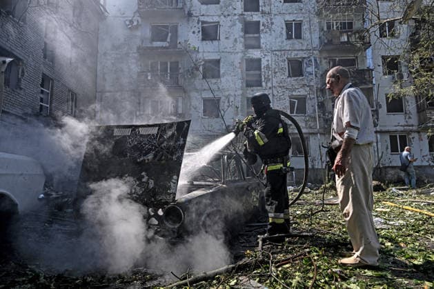 A man watches a firefighter extinguish a fire in a car destroyed by a Russian air strike, Zaporizhzhia, Ukraine, August 10, 2026. Russian forces attacked civilian infrastructure in the regional capital and the Zaporizhzhia district with guided aerial bombs. Apartment blocks and private houses were damaged, and cars were wrecked. At least 24 people were injured, including two children. (Photo by Dmytro Smolienko Ukrinform) Russian army attacks Zaporizhzhia with guided bombs again  Copyright: xDmytroxSmolienkox