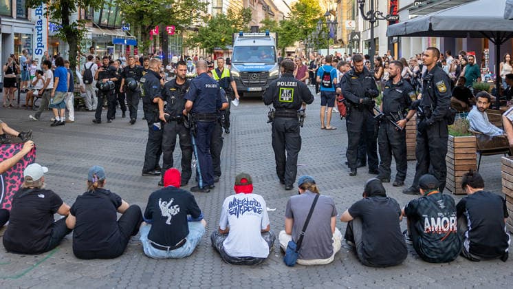 Polizeieinsatz bei Montagsdemo von Team Menschenrechte und Gegenprotesten, Nürnberg, 10.087.2026 In der Karolinenstraße blockiert eine Gruppe von Gegendemonstranten sitzend den Demonstrationszug von Team Menschenrechte . Zahlreiche Polizeibeamte in Einsatzkleidung stehen zwischen den Sitzenden und den Passanten, im Hintergrund ein Einsatzfahrzeug der Polizei. Nürnberg Bayern Deutschland *** Police operation during the Monday demonstration by Team Menschenrechte and counter-protests, Nuremberg, 10 087 2026 On Karolinenstraße, a group of counter-protesters is sitting down to block the march organized by Team Menschenrechte. Numerous police officers in tactical gear stand between the seated protesters and passersby; in the background is 20260810-6V2A0667-M4000