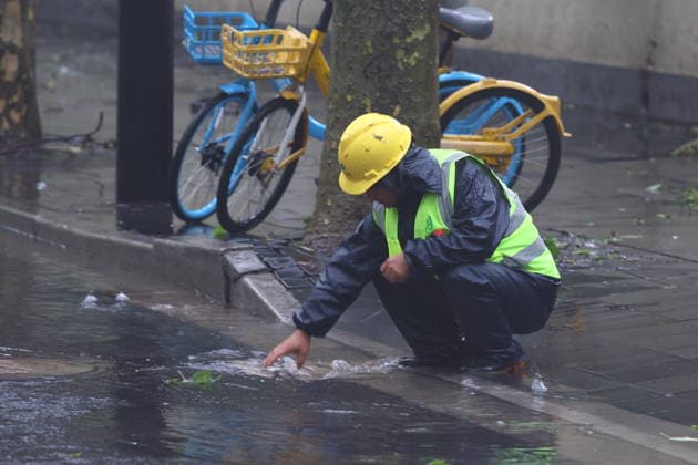 SHANGHAI, CHINA - AUGUST 10: A sanitation worker clears a blocked sewer with bare hands on Wukang Road as Typhoon Dolphin brings heavy rain and flooding on August 10, 2026 in Shanghai, China. The typhoon caused extreme rainfall in some areas, leading to waterlogging on multiple road sections.  Copyright: xVCGx 111659181691