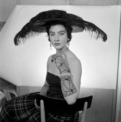 Hutmode 1954 Model Gina im improvisierten Foto-Studio in München, 1954. Gina sitzt auf einem Stuhl, trägt ein extravagantes Hutmodel mit schwarzen Federn, dazu lange Edelstein-Ohrringe und schwarze Spitzenhandschuhe. Scan vom Negativ. München Deutschland Copyright: KlausxRedenbacher RED_93020000215 EDITORIAL USE ONLY