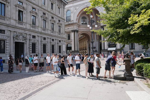 IPA87397521 - Milan, August 11, 2026: It’s hot in Milan. The heat wave continues, and tourists are shielding themselves from the sun with clothing, umbrellas, and hats, and are cooling off or drinking water at the fountain in Piazza Scala.  Copyright: xDuilioxPiaggesix xDuilioxPiaggesix 87397521