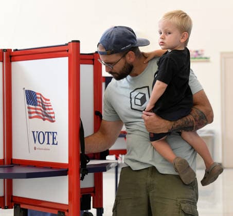 August 11, 2026, Racine, Wisconsin, USA: TYLER SCHEER, with his son CALLAHAN, 2, votes at Fratt Elementary School in Racine in the Wisconsin primary election Tuesday August 11, 2026. National focus is on the Democratic gubernatorial primary and on efforts to flip several Republican congressional seats, including that of incumbent Bryan Steil who represents the First Congressional District, including Racine County. Racine USA  - ZUMAh154 20260811_znp_h154_009 Copyright: xMarkxHertzbergx